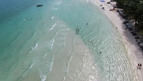 Drone-aerial-view-in-Vietnam-flying-over-Phu-Quoc-island-Sao-beach,-white-sand,-crystal-clear-blue-turquoise-water,-palm-trees-forest-and-people-walking-and-swimming-on-a-sunny-day