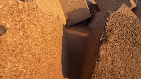 Concrete-blocks-and-cubes-along-the-beach,-where-coastal-defense-structures-emerge,-partially-submerged-in-sand