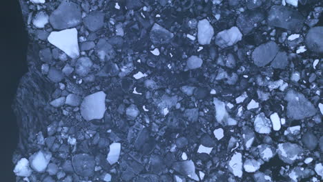 Chunks-of-broken-polar-ice-floating-at-surface-of-Arctic-ocean,-top-down-aerial