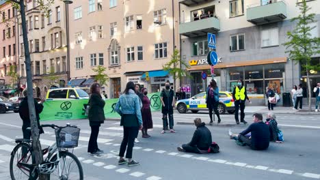 Demonstranten-Setzen-Sich-Bei-Demonstration-In-Stockholm-Hin,-Polizeiauto-Fährt-Vorbei