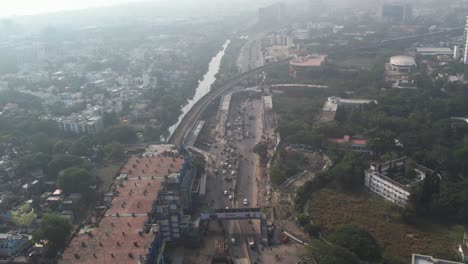 Aerial-drone-shot-of-metro-station-in-the-middle-of-the-city-with-traffic-and-lake-in-Indian-city