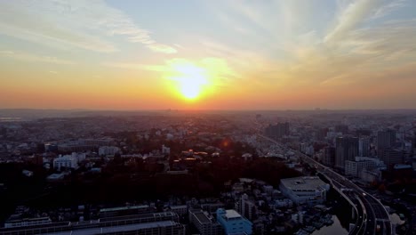 Sunset-over-a-bustling-cityscape-with-warm-hues-and-clear-skies,-aerial-view