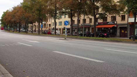 El-Autobús-Azul-Deja-Una-Parada-En-La-Calle-Con-Tráfico-De-Automóviles-En-Otoño-De-Estocolmo