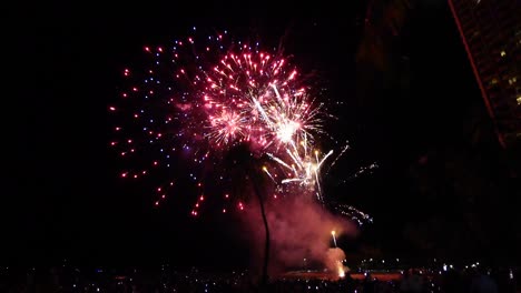 Multitudes-De-Personas-Viendo-Un-Colorido-Espectáculo-De-Fuegos-Artificiales-En-La-Playa-De-Waikiki,-Honolulu,-Oahu,-Hawai.