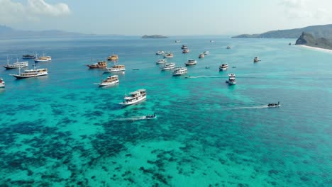 Flight-over-turquoise-water-and-boats-of-Pantai-Merah-On-Padar-Island-in-Komodo-National-Park,-Indonesia