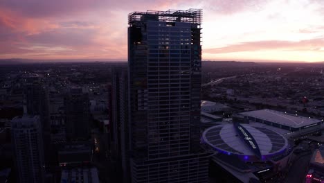 Aerial-high-and-wide-panning-shot-of-the-unfinished-Oceanwide-Plaza-luxury-towers-covered-in-graffiti-art-at-sunset-in-downtown-Los-Angeles,-California