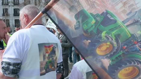 A-protestor-holds-a-flag-depicting-a-picture-of-a-tractor-as-farmers-and-agricultural-unions-protest-against-unfair-competition,-agricultural-and-government-policies