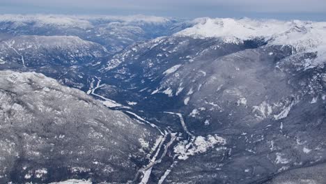 Alta-Vista-Aérea-Del-Valle-Montañoso-Cubierto-De-Nieve-En-Un-Sombrío-Día-De-Invierno