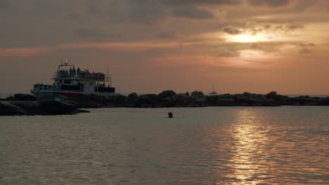Schwimmen-Bei-Sonnenuntergang-Und-Boote,-Die-Sich-Im-Wasser-Vor-Curaçao-In-Der-Karibik-Bewegen