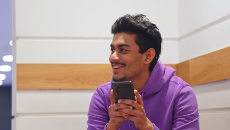 Young-man-nodding-happily-to-someone-off-camera-with-smartphone-on-hands