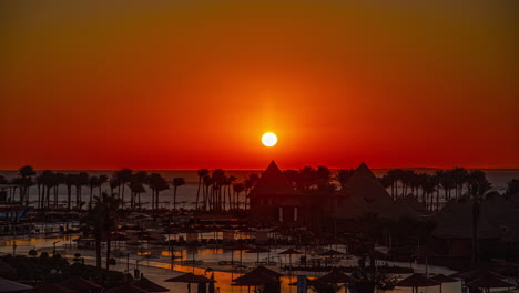 Zeitraffer-Des-Sonnenaufgangs-In-Einem-Hotel-In-Ägypten-Am-Strand-Mit-Der-Sonne-Am-Horizont,-Palmen,-Pool-Und-Natur
