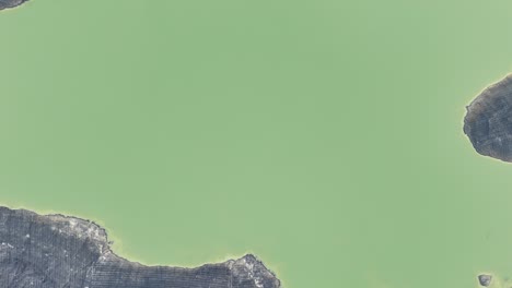 Aerial-drone-view-of-a-very-large-dam,-artificial-lake-surrounded-by-mountains