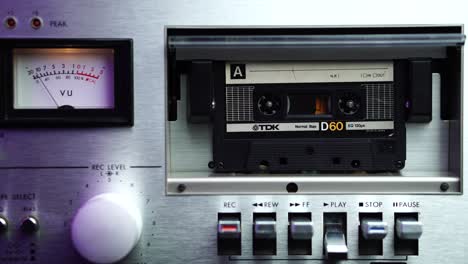 Audiokassette-Einlegen-Und-Auf-Einem-Vintage-Player-Mit-VU-Metern-In-Nahaufnahme-Die-Wiedergabetaste-Drücken