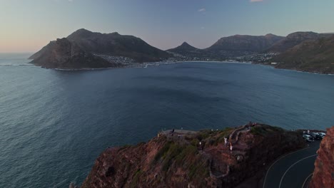 Vuele-Sobre-Chapman&#39;s-Peak-Drive-Con-Vistas-A-La-Bahía-De-Hout-Durante-La-Puesta-De-Sol-En-Ciudad-Del-Cabo,-Sudáfrica