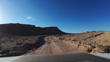 FPV-Fahren-Auf-Einer-Leeren-Unbefestigten-Wüstenstraße-An-Einem-Sonnigen-Tag,-Bentonit-Hügel,-Utah