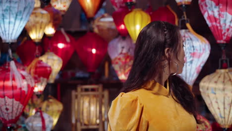 Attractive-Vietnamese-woman-in-yellow-outfit-looks-at-lantern-shop-in-Hoi-An-at-night