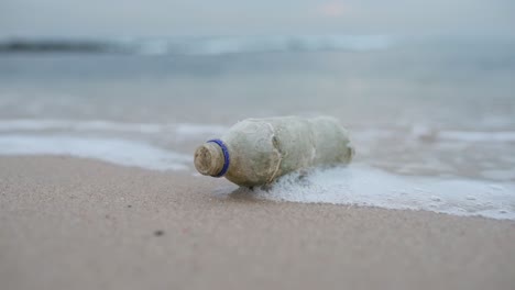 Wellen,-Die-über-Eine-Verlassene-Plastikflasche-An-Einem-Strand-Schwappen