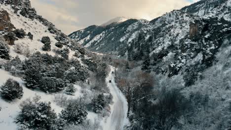 Aerial-tracking-shot-of-vehicles-driving-through-a-snowy-canyon-in-Utah