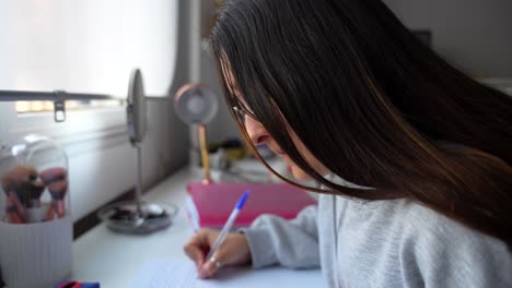 Girl-focused-on-writing-notes-at-her-desk