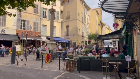 People-walk-by-bars-at-Place-des-Augustins-in-Aix-en-Provence,-France