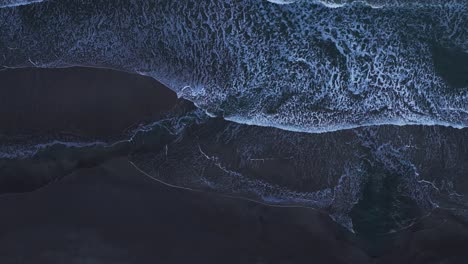 Drone-aerial-view-looking-straight-down-over-white-waves-crashing-on-a-beach