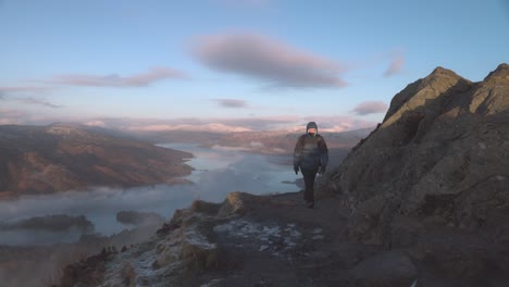 Static-shot-of-a-hiker-admiring-thew-views-at-the-summit-of-Ben-A'an-over-a-loch