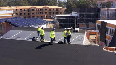 Aerial-close-up-panning-shot-of-a-construction-crew-working-on-the-roof-of-a-pre-fabricated-housing-module-at-a-building-site-in-West-Los-Angeles,-California