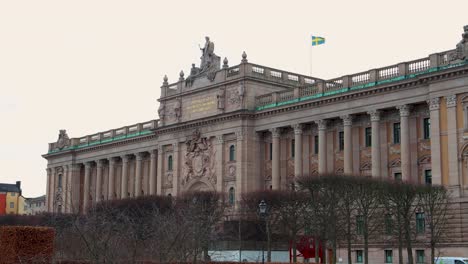 Schwedisches-Parlamentsgebäude-Mit-Flagge-Oben-An-Einem-Bewölkten-Tag,-Stockholm