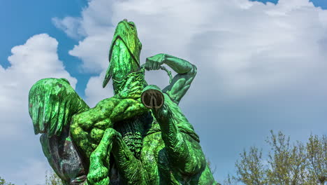 White-clouds-pass-by-a-green-dragon-statue-against-a-blue-sky