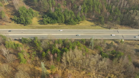 Capture-the-seamless-blend-of-technology-and-nature-with-an-aerial-view-of-a-highway-cutting-through-a-verdant-forest,-illustrating-the-dynamic-flow-of-traffic-amidst-the-tranquility-of-woodland