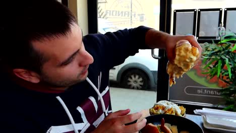 Man-carefully-picks-up-hamburger-from-plate-dripping-cheese,-looking-excited