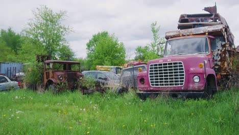 wide-shot-of-a-couple-old-rusted-out-trucks-sitting-in-a-field-rusting-from-the-elements