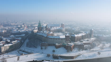 Panorama-of-snow-covered-Wawel-castle-and-Old-Town-at-magic-morning-with-soft-sun-light-during-winter,-Krakow,-Poland