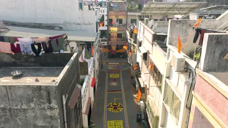 Vista-Aérea-Del-Dron,-La-Cámara-Del-Dron-Avanza-Donde-El-Rangoli-De-Jai-Shri-Ram-Es-Visible-En-La-Carretera-Grande-Y-La-Gente-Observa-Tanto-El-Rangoli-Como-El-Dron-Desde-Arriba