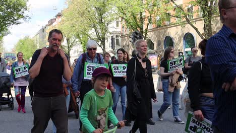 Familias-Marchan-Con-Carteles-De-Detener-El-Ecocidio-En-Una-Manifestación-De-Protesta-Climática,-Slomo