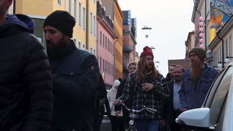 Men-with-long-hair,-beards-and-hats-walk-on-busy-street-in-Stockholm