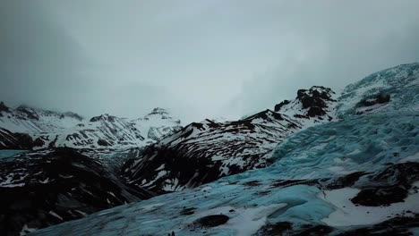 Vista-Aérea-De-Drones-De-Personas-Caminando-En-Un-Enorme-Campo-De-Glaciares-Azules-En-Islandia,-Tierra-De-Fuego-Y-Hielo