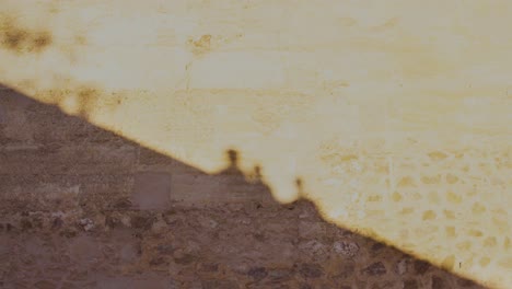 Shadow-on-orange-ancient-wall-of-three-peoples-walking