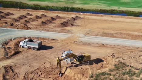 Yarrawonga,-Victoria,-Australia---8-March-2024:-Excavator-operator-working-hard-to-load-two-tip-trucks-with-dirt-on-a-new-site-at-Silverwoods-Estate-in-Yarrawonga