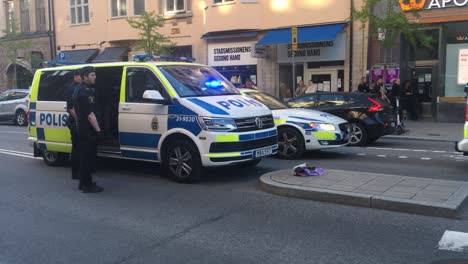 Officers-by-still-police-cars-with-sirens-on-in-Stockholm,-Sweden