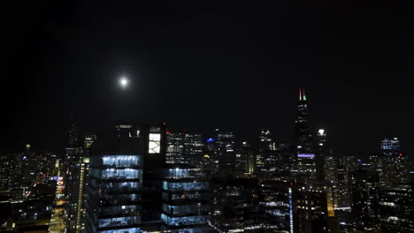 Aerial-view-of-full-moon-above-the-Fulton-market-and-the-skyline,-night-in-Chicago