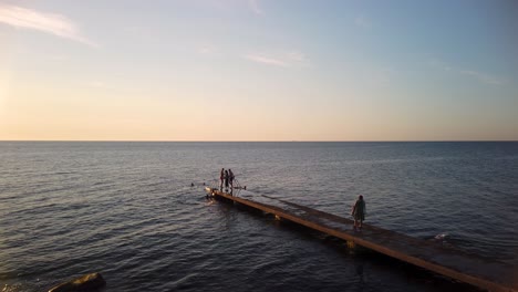 Children-swim-by-end-of-jetty-with-open-ocean-in-background,-slomo