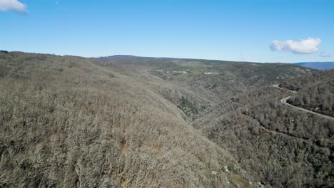 Panoramic-aerial-reveal-of-Navea-River-and-winding-road-and-trail-on-hillside