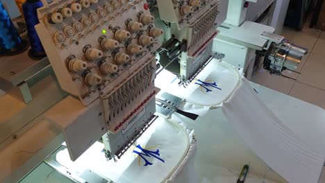 Top-down-view-of-computerized-textile-embroidery-sewing-machine-automatically-embroidering-pattern-design-onto-fashion-clothing