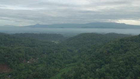 Vista-Aérea-Del-Valle-Entre-Colinas-Con-Densos-Bosques