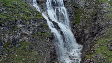 Majestic-Cascata-di-Stroppia-waterfall-flowing-into-Lago-Niera,-surrounded-by-rocky-cliffs