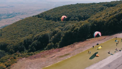Paragliders-flying-over-a-forest-enjoying-the-view-from-up-in-the-air