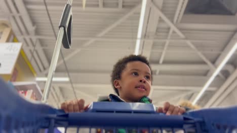 Niño-Negro-De-4-Años-Empujando-Un-Carrito-De-Compras-En-Un-Supermercado