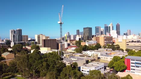 Toma-Aérea-Lenta-En-Reversa-De-Una-Grúa-Torre-En-Un-Sitio-De-Construcción-Con-Edificios-De-La-Ciudad-De-Perth-Al-Fondo