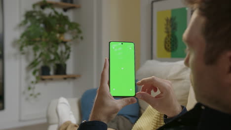 Kaukasischer-Mann-Benutzt-Mobiltelefon-Mit-Grünem-Bildschirm-Im-Haus